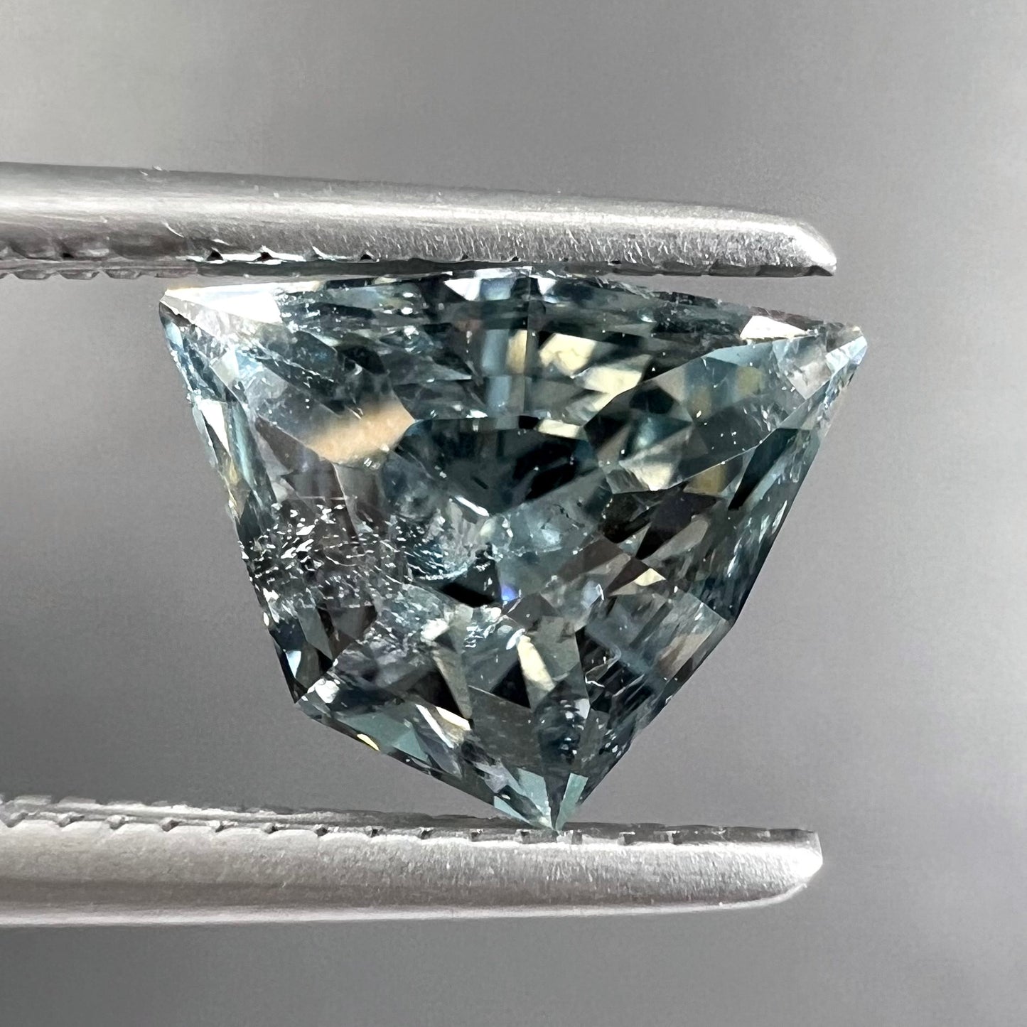 A loose, freeform shield cut tourmaline gemstone.  The stone is a steel blue color.