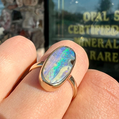 Ladies' yellow gold solitaire ring bezel set with a natural green striped boulder opal from Quilpie, Australia.