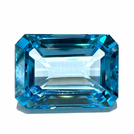 An emerald cut Swiss blue topaz gemstone.  The stone is an electric blue color.