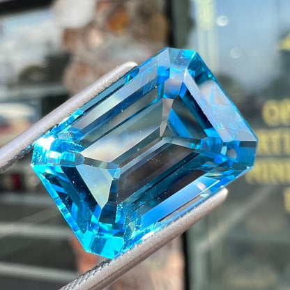 An emerald cut Swiss blue topaz gemstone.  The stone is an electric blue color.