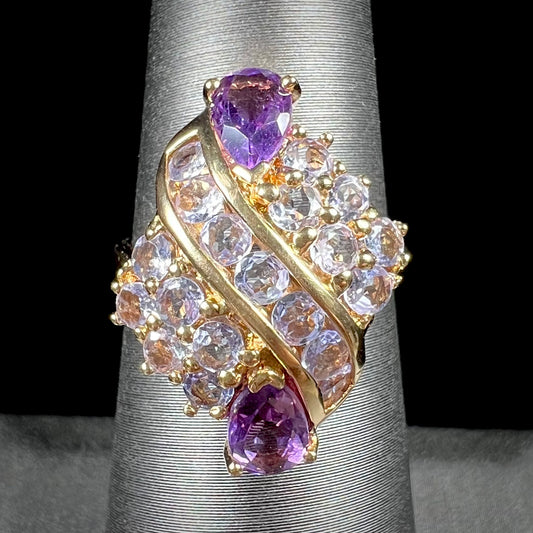 A ladies' gold ring set with a cluster of round tanzanites and two pear shaped amethyst accent stones.