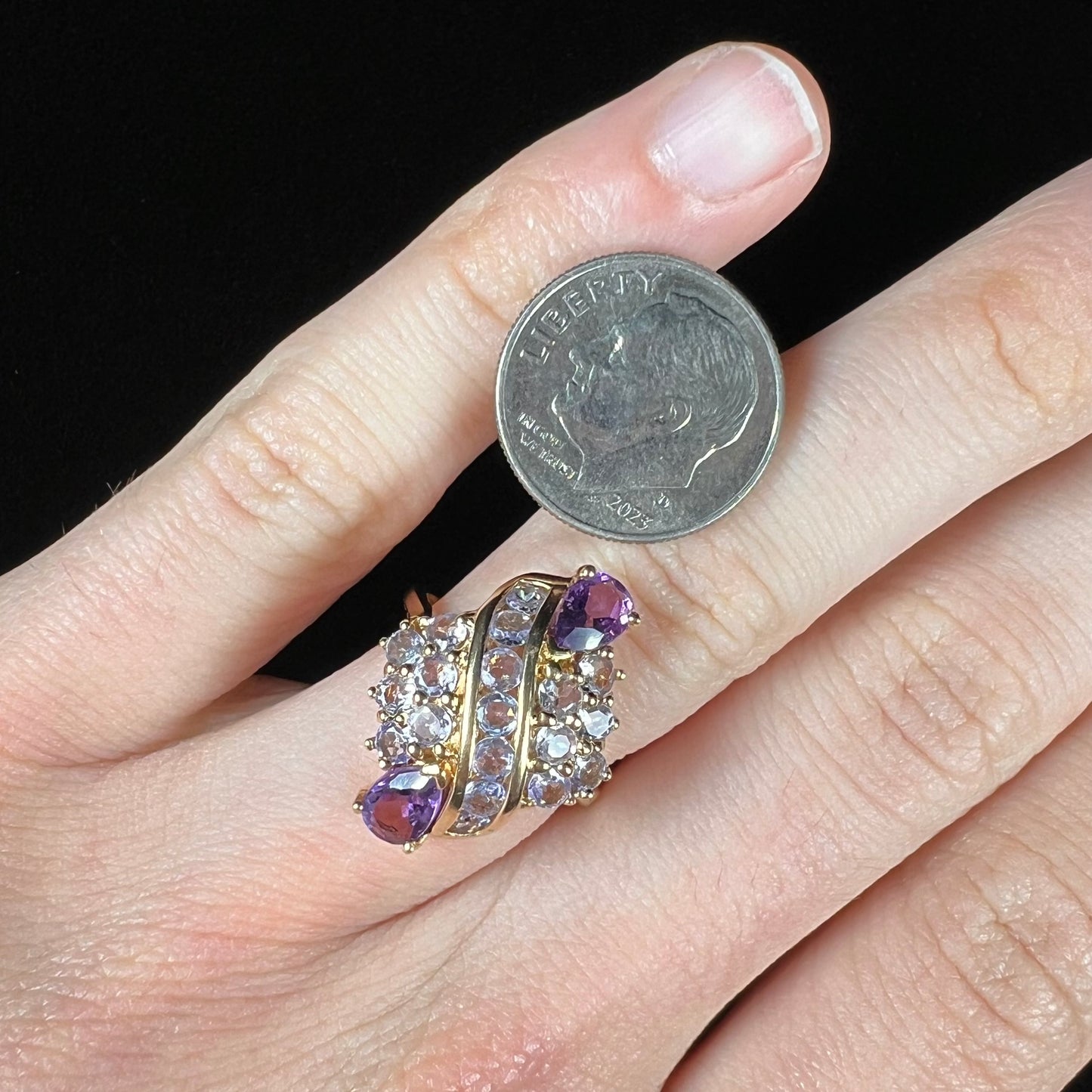 A ladies' gold ring set with a cluster of round tanzanites and two pear shaped amethyst accent stones.