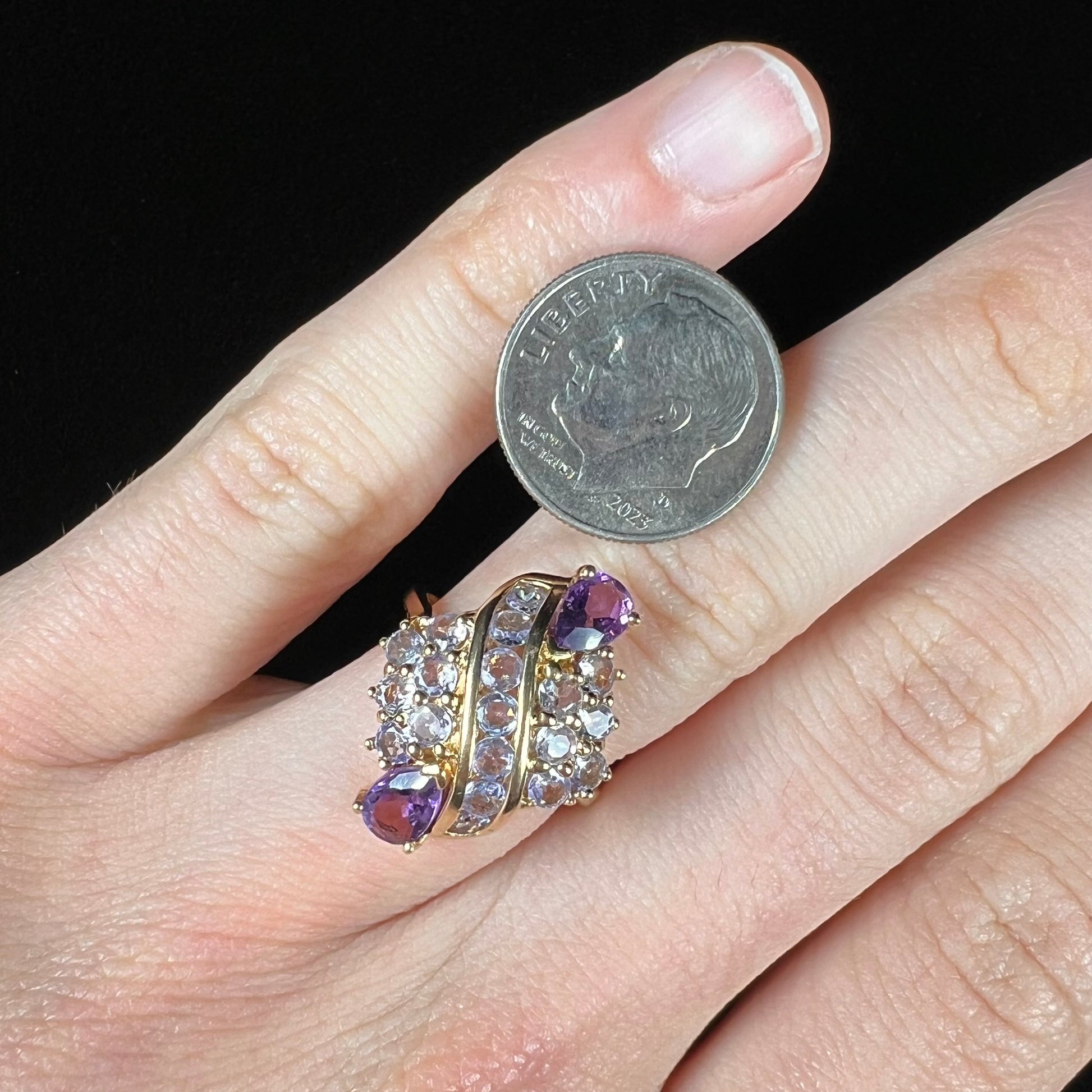 A ladies' gold ring set with a cluster of round tanzanites and two pear shaped amethyst accent stones.