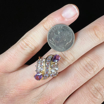 A ladies' gold ring set with a cluster of round tanzanites and two pear shaped amethyst accent stones.