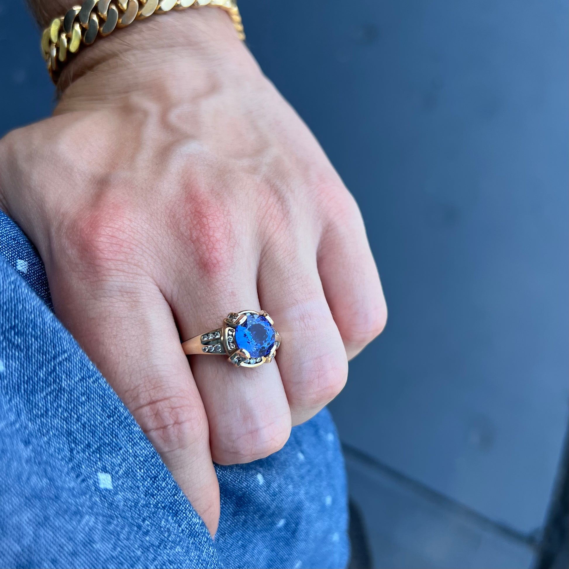 A ladies' yellow gold natural tanzanite and diamond ring.  Diamonds are channel set along the shank and in the prongs.