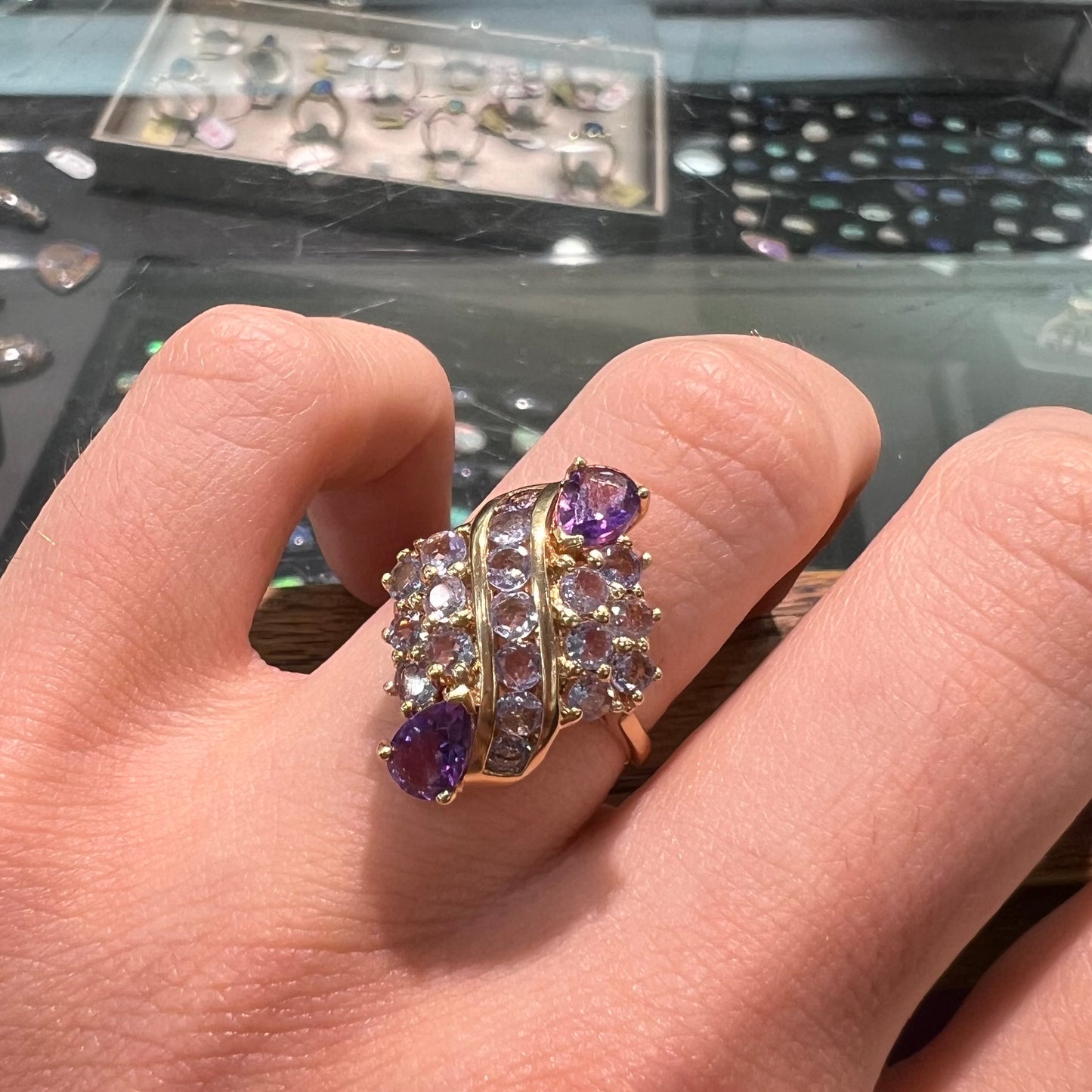 A ladies' gold ring set with a cluster of round tanzanites and two pear shaped amethyst accent stones.