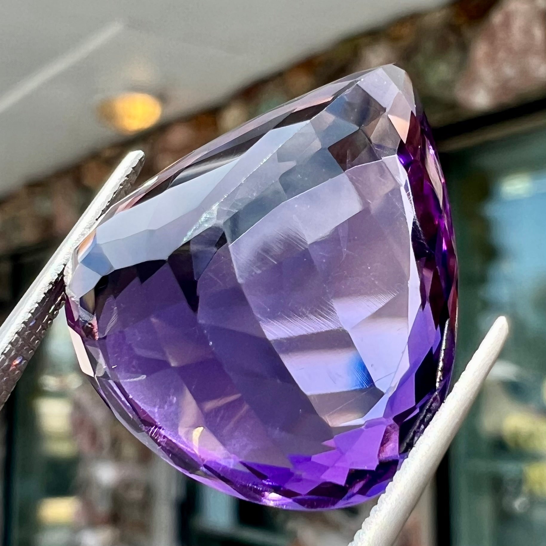 A large, pear shaped amethyst gemstone.  The stone is a dark purple color.