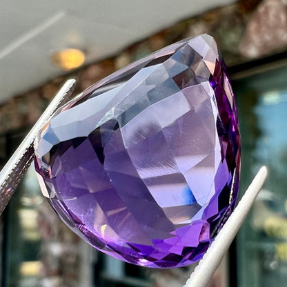 A large, pear shaped amethyst gemstone.  The stone is a dark purple color.