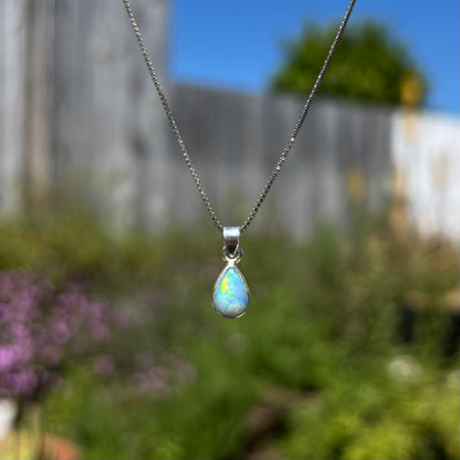 A dainty, sterling silver necklace bezel set with a natural, pear shaped opal stone.