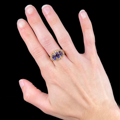 A ladies' three stone iolite ring in yellow gold set with diamond and B grade tanzanite accents.