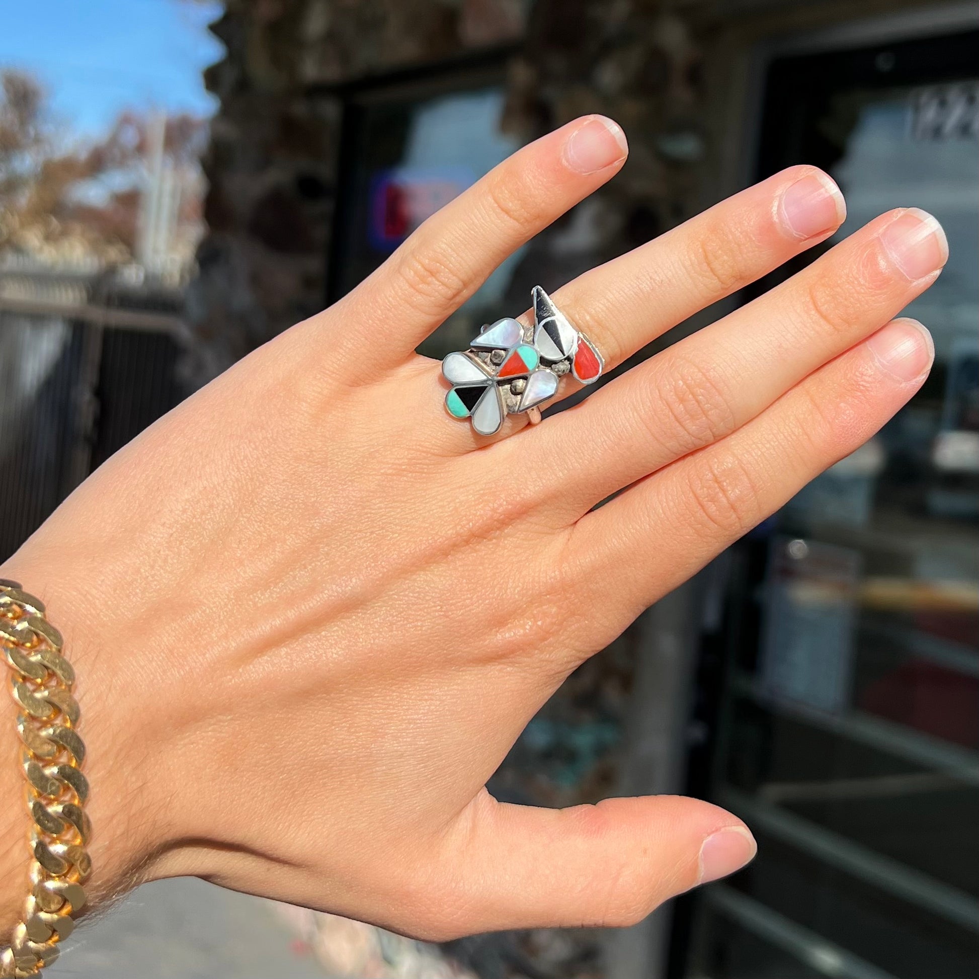 A vintage, sterling silver Zuni thunderbird ring inlaid with turquoise, mother of pearl, onyx, and coral stones.