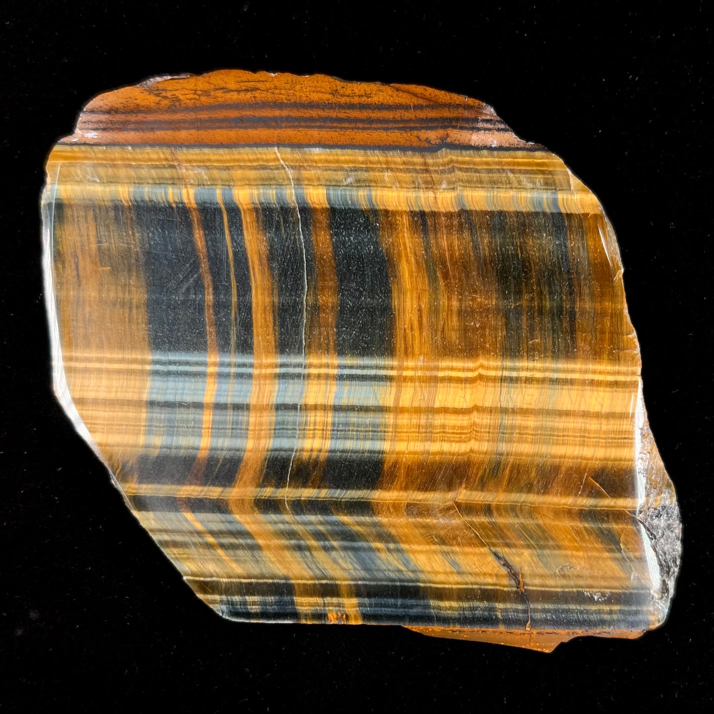 A polished slab of yellow tiger's eye with blue streaks.