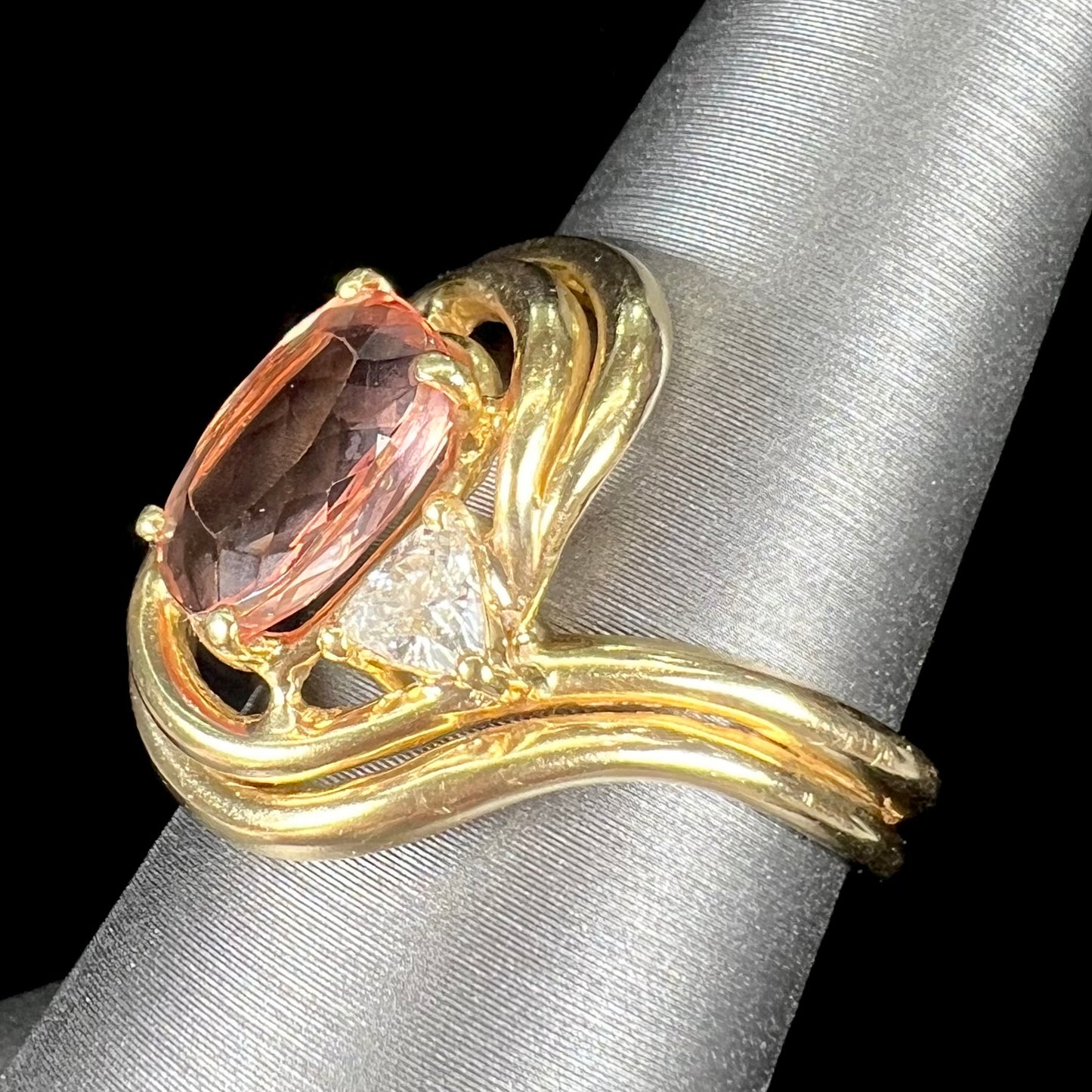 An 18 karat yellow gold ring set with two triangle cut diamonds and a cushion cut imperial topaz.