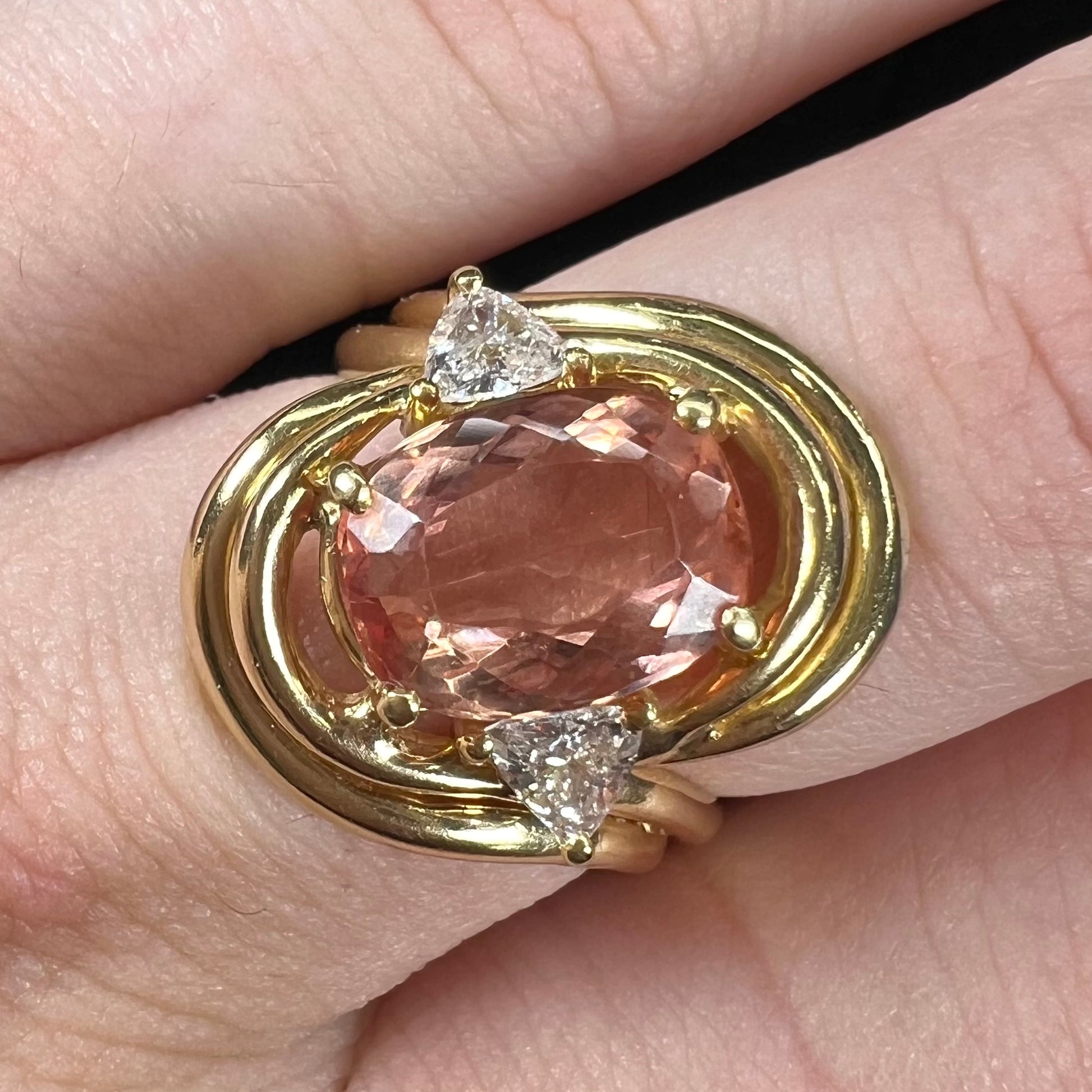 An 18 karat yellow gold ring set with two triangle cut diamonds and a cushion cut imperial topaz.