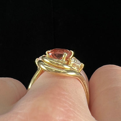 An 18 karat yellow gold ring set with two triangle cut diamonds and a cushion cut imperial topaz.