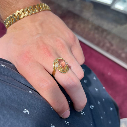 An 18 karat yellow gold ring set with two triangle cut diamonds and a cushion cut imperial topaz.