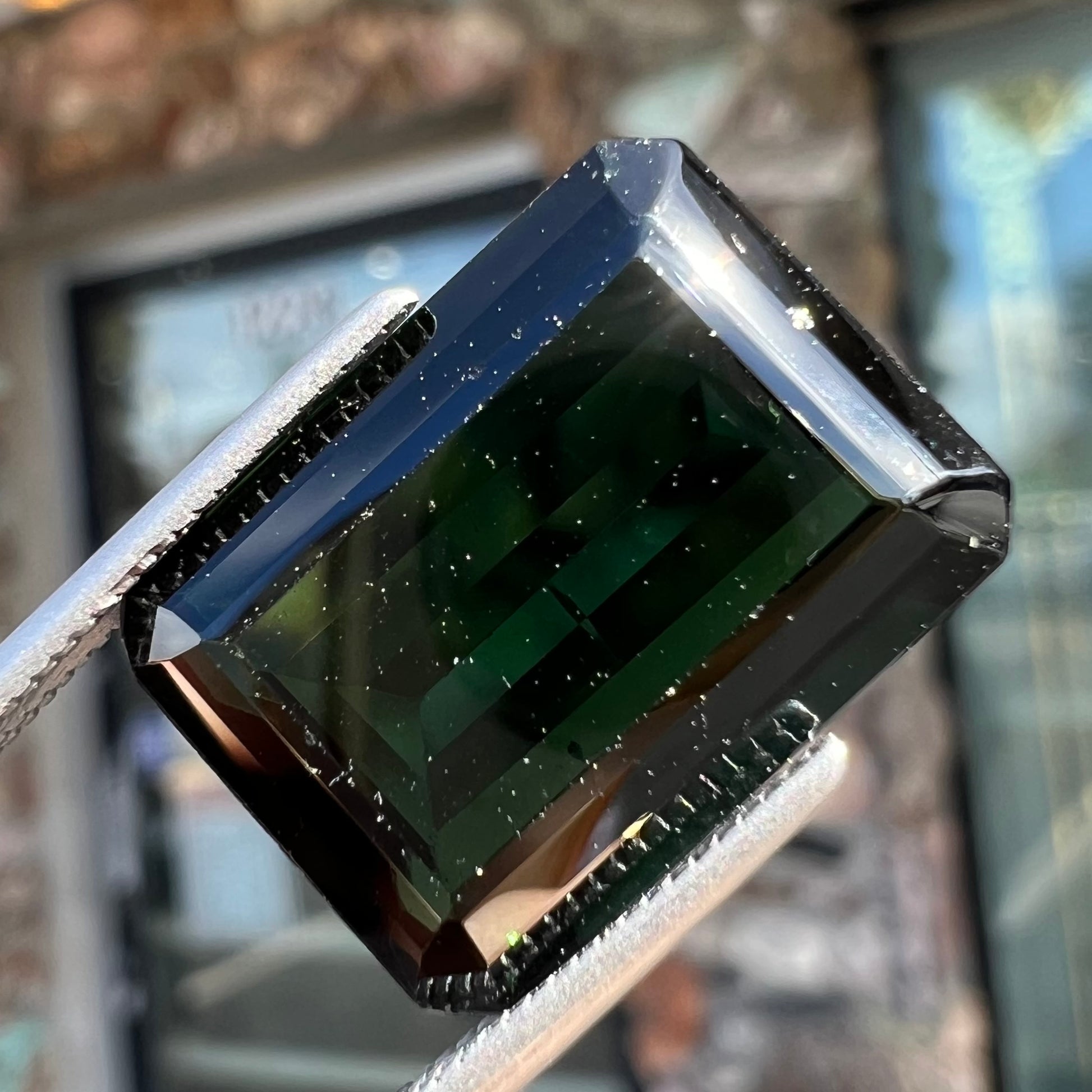 A faceted emerald cut dark green tourmaline gemstone.