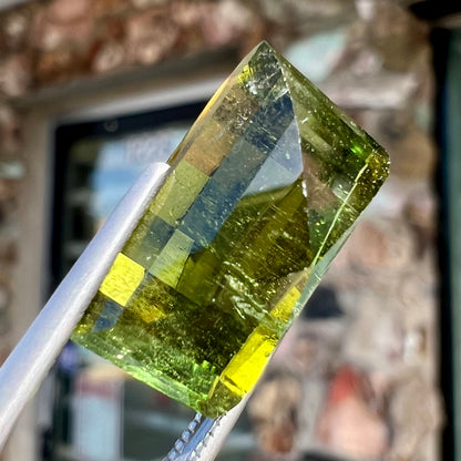 A rectangular step-cut yellowish green tourmaline gemstone.