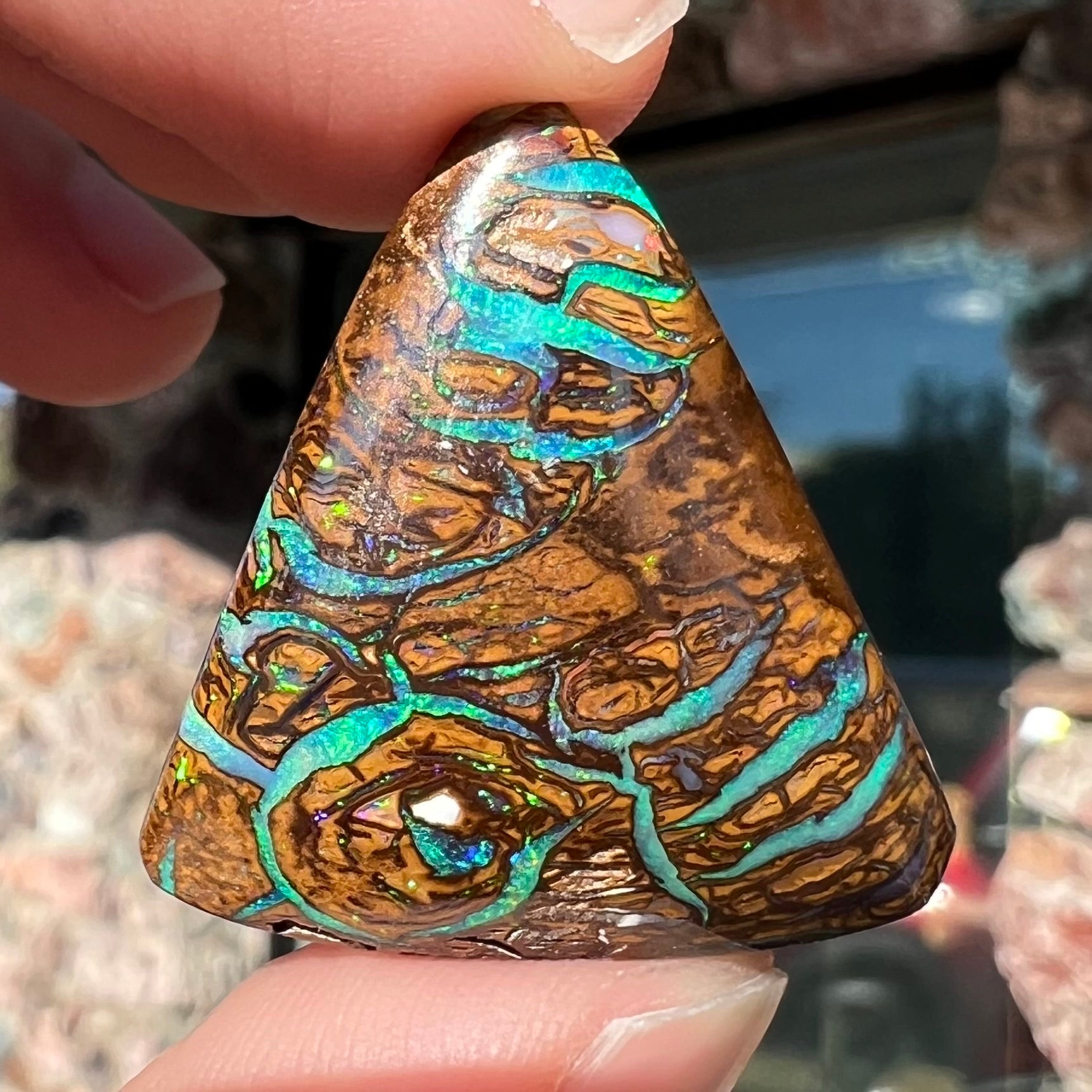 A triangle shaped Koroit boulder opal.  The stone has blue veins of opal running through it.