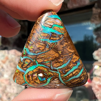 A triangle shaped Koroit boulder opal.  The stone has blue veins of opal running through it.