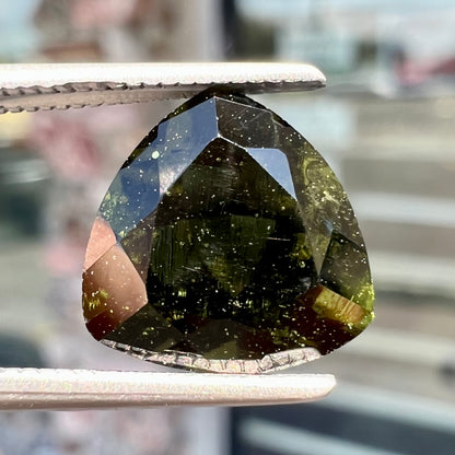 A natural, trillion cut moldavite gemstone.