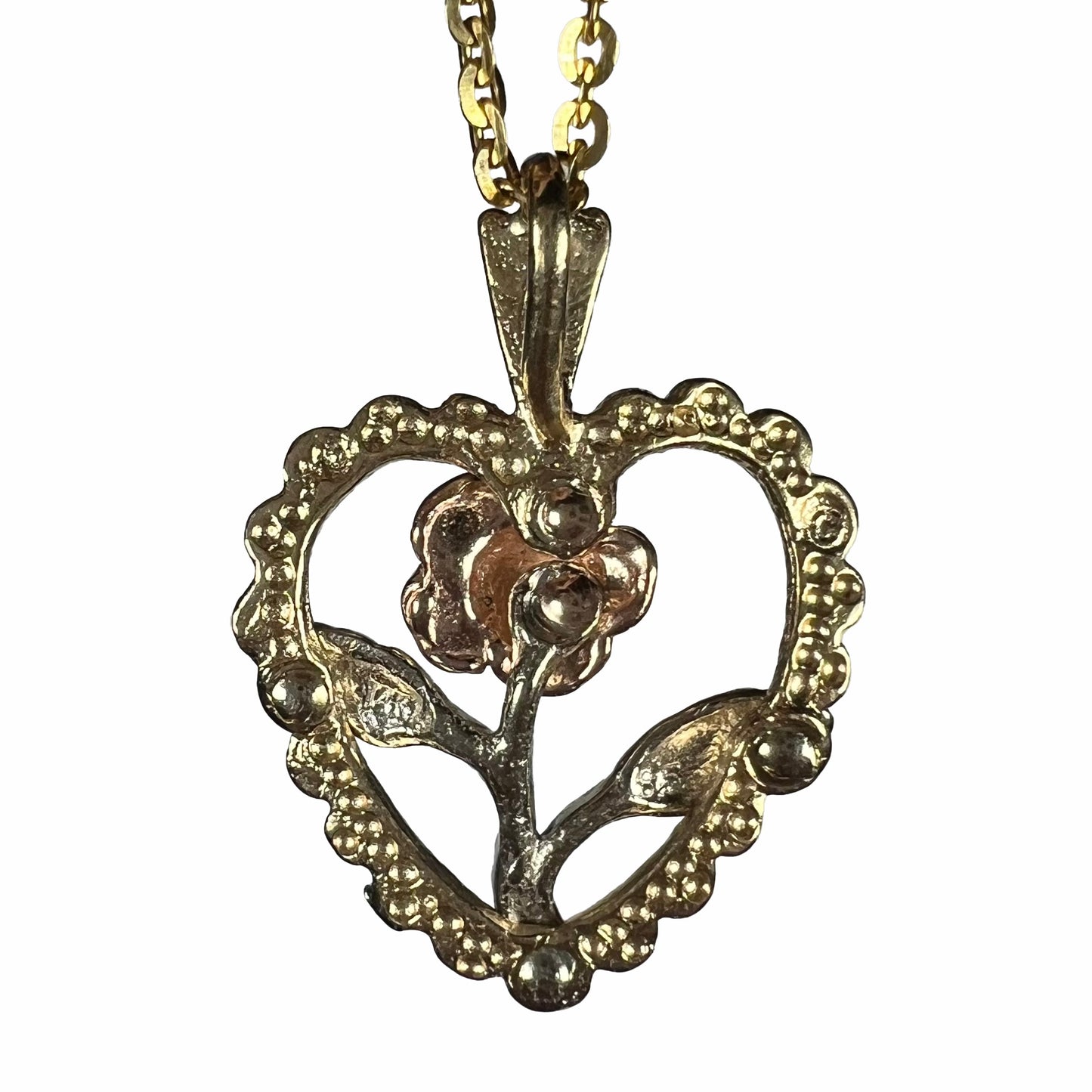 A tricolor gold pendant featuring the design of a heart with a flower in the middle of it.