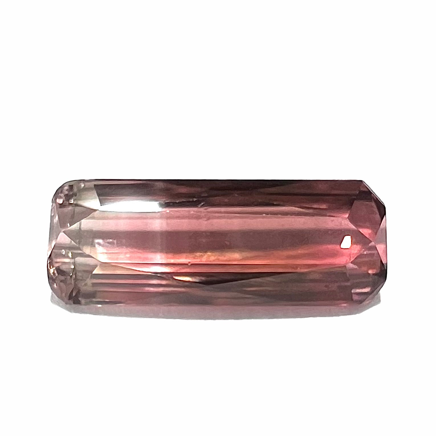 A loose, modified emerald cut tricolor tourmaline.  The stone transitions from pink to light pink to white colors.