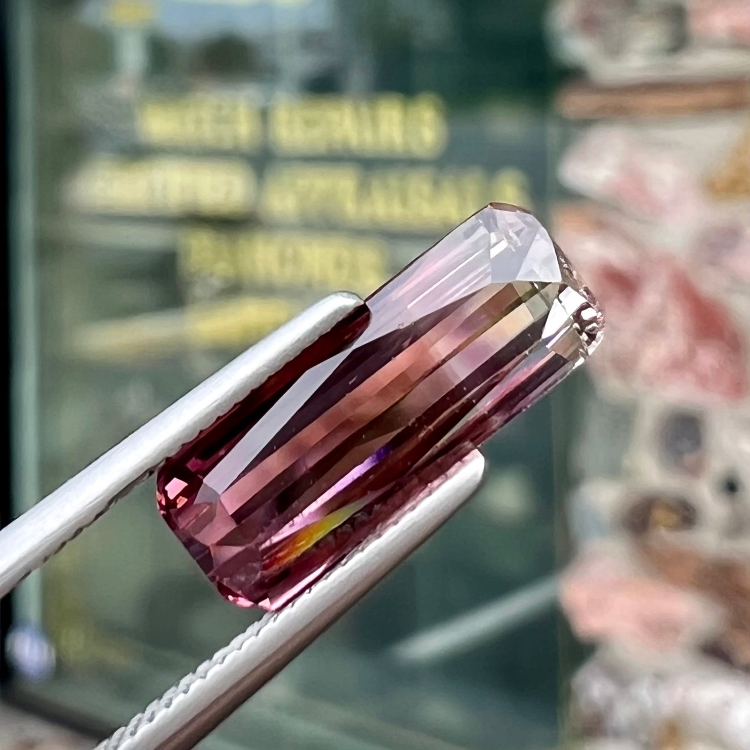 A loose, modified emerald cut tricolor tourmaline.  The stone transitions from pink to light pink to white colors.