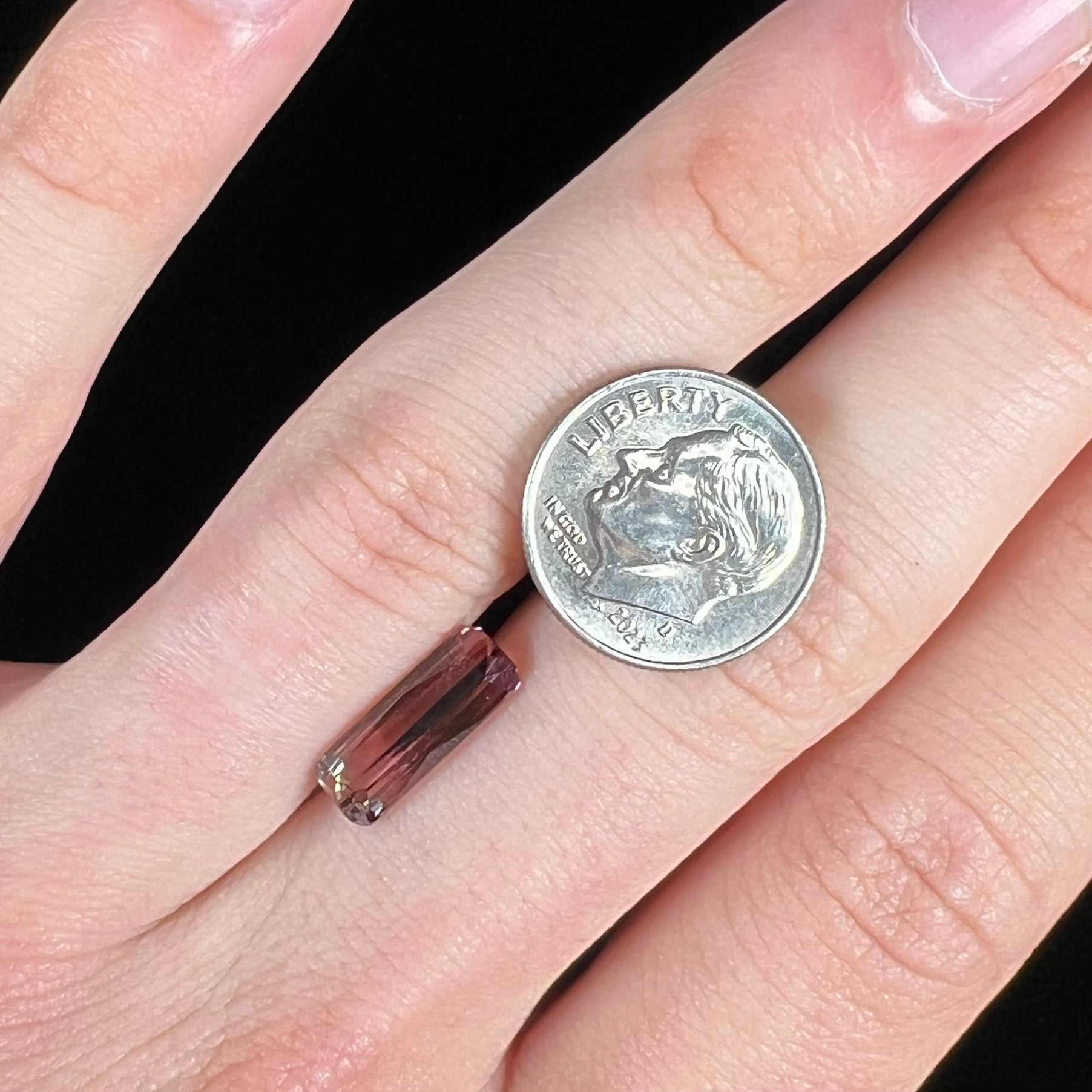 A loose, modified emerald cut tricolor tourmaline.  The stone transitions from pink to light pink to white colors.