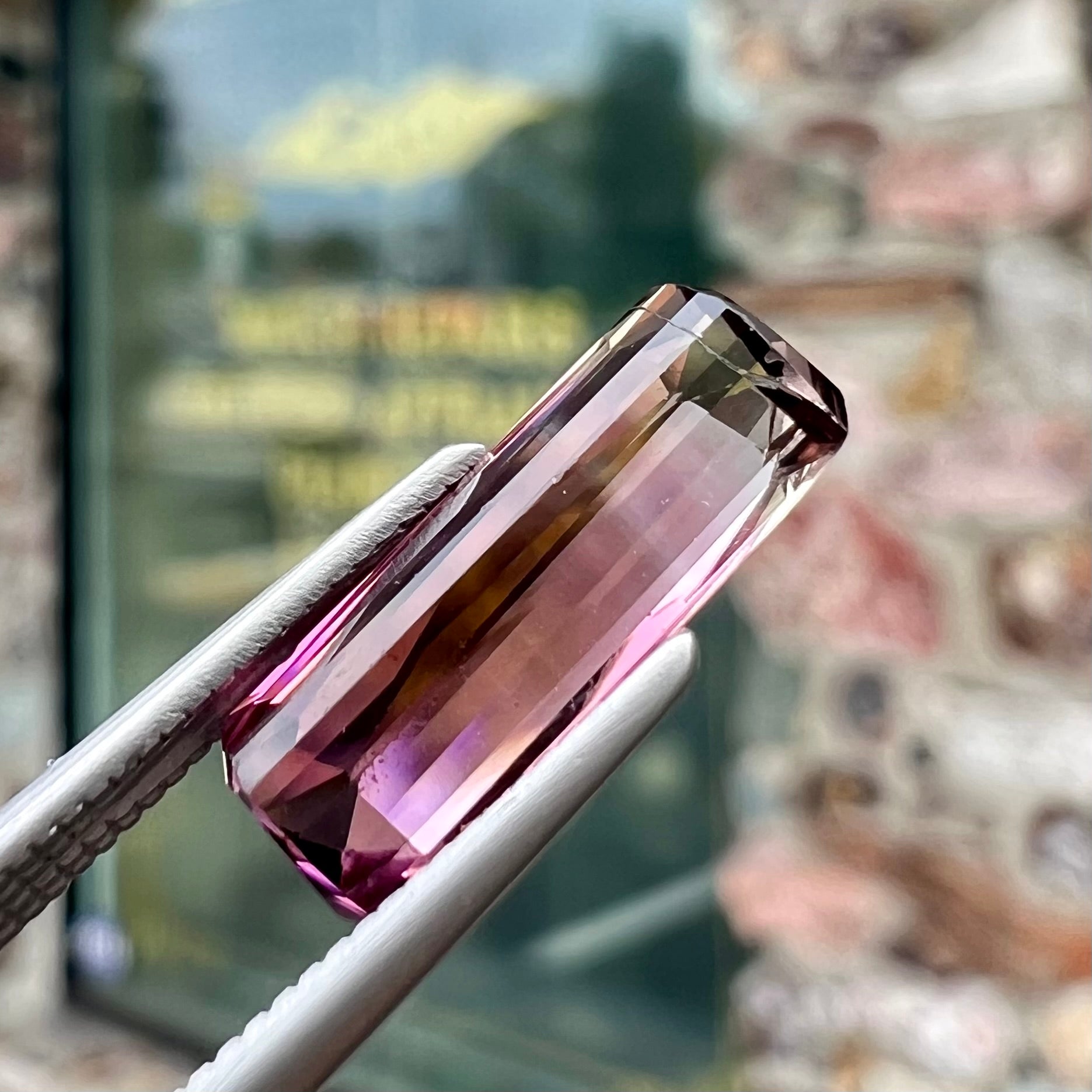 A loose, modified emerald cut tricolor tourmaline.  The stone transitions from pink to light pink to white colors.