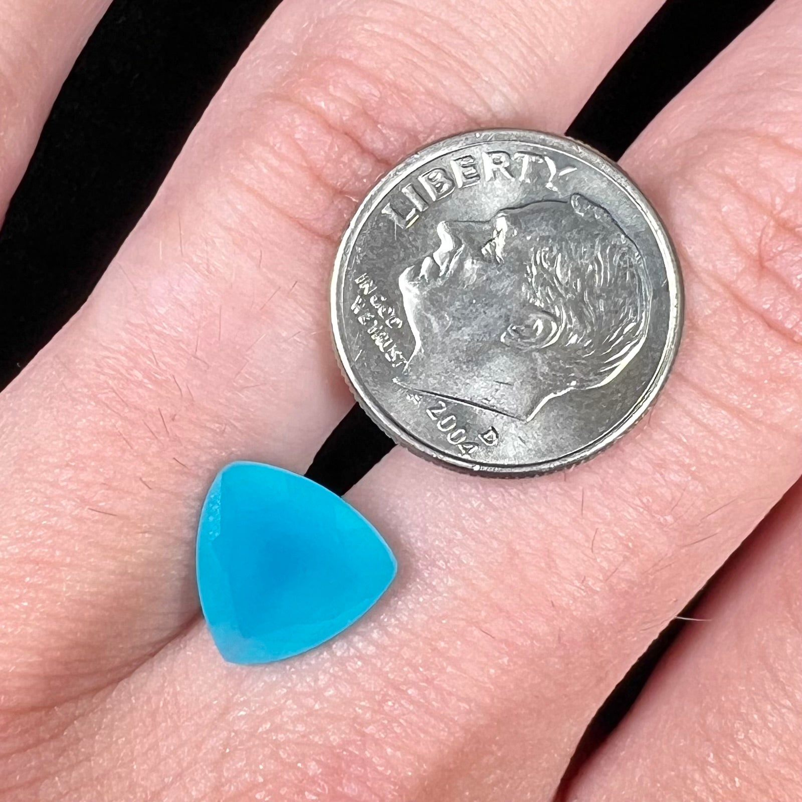 A loose, blue, trillion cut Paraiba chalcedony gemstone.