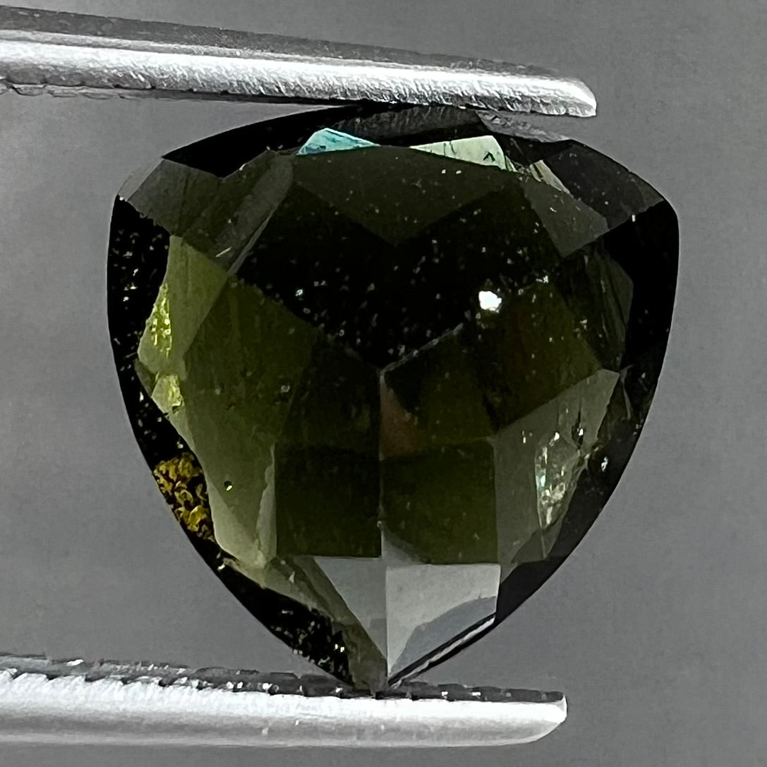 A natural, trillion cut moldavite gemstone.