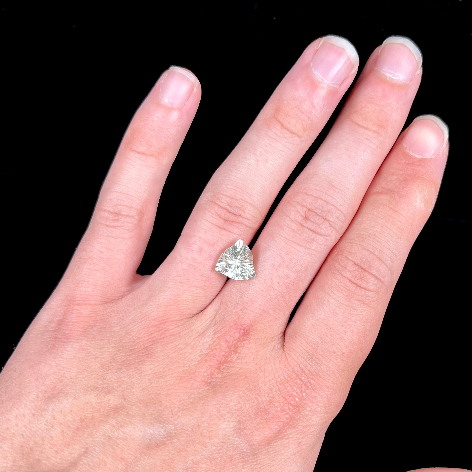 A loose, triangular fantasy cut prasiolite gemstone.  Prasiolite is a light green variety of quartz.