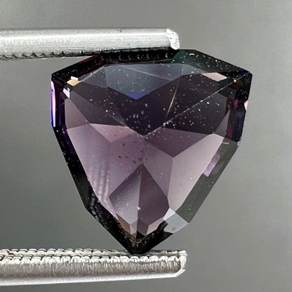 A loose, natural purple trillion cut spinel gemstone.