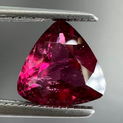 A loose, trillion cut rubellite tourmaline gemstone.