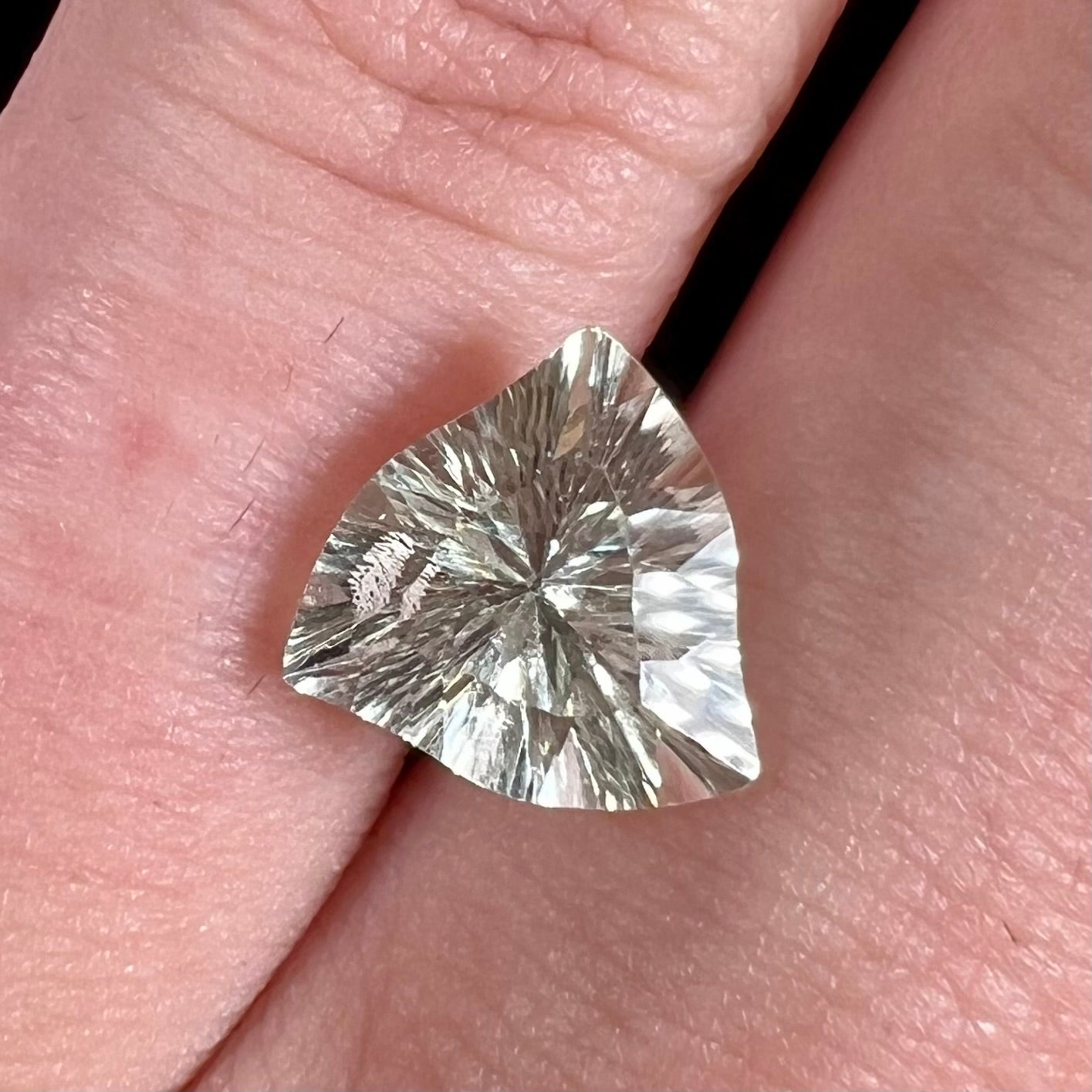 A loose, triangular fantasy cut prasiolite gemstone.  Prasiolite is a light green variety of quartz.