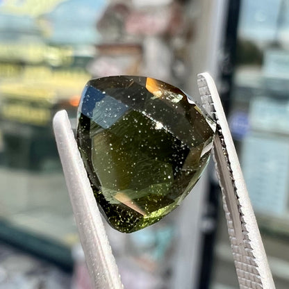 A natural, trillion cut moldavite gemstone.