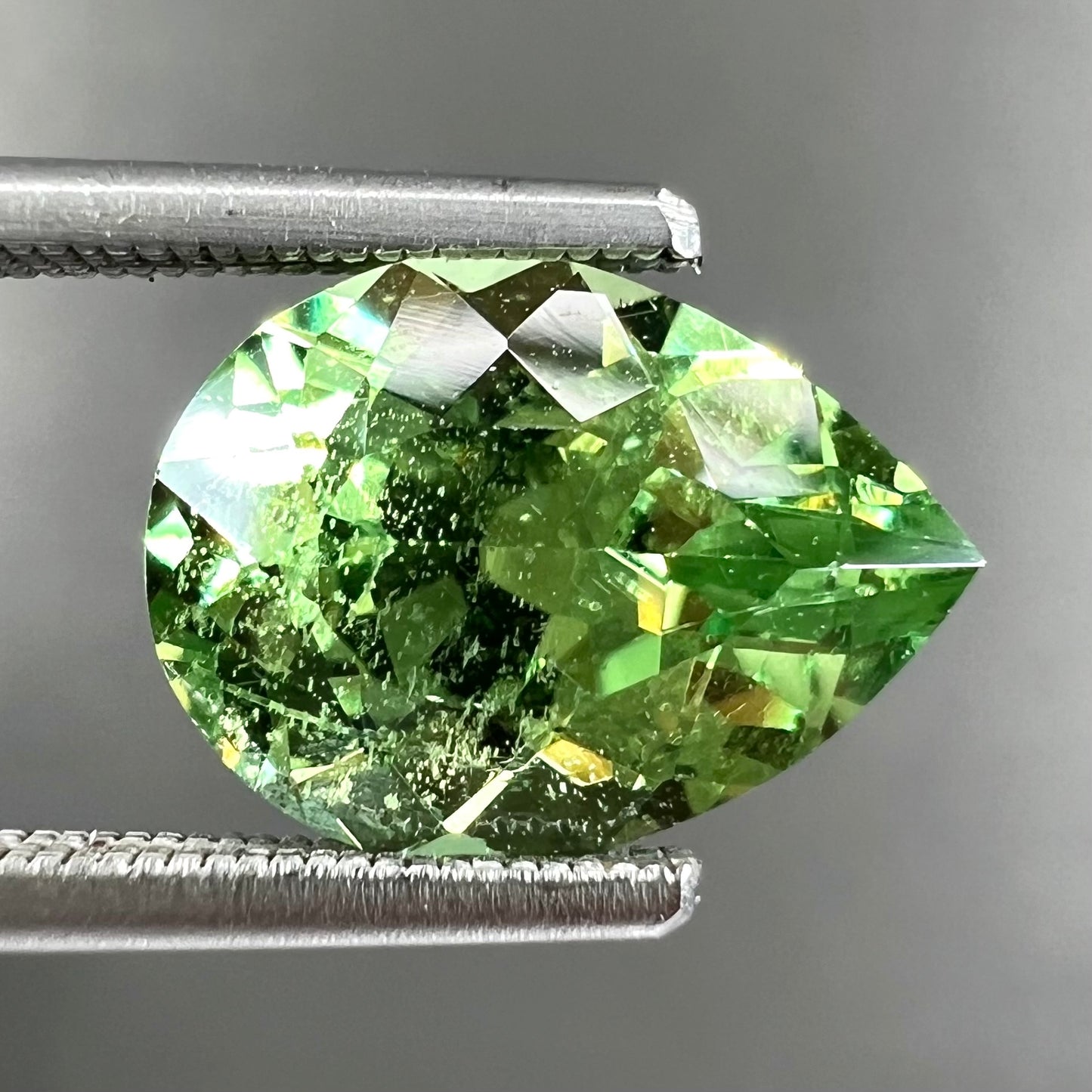 A loose, pear shaped tsavorite garnet gemstone.  The stone is yellowish green.