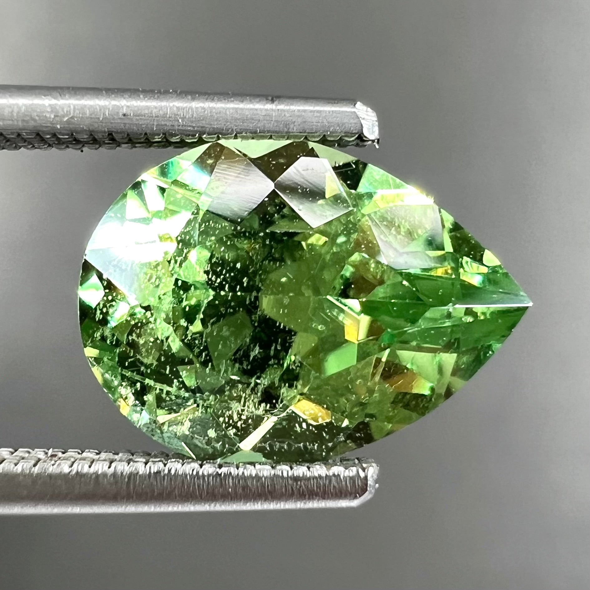 A loose, pear shaped tsavorite garnet gemstone.  The stone is yellowish green.