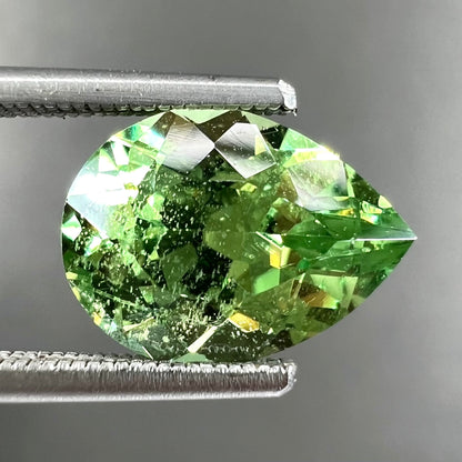 A loose, pear shaped tsavorite garnet gemstone.  The stone is yellowish green.