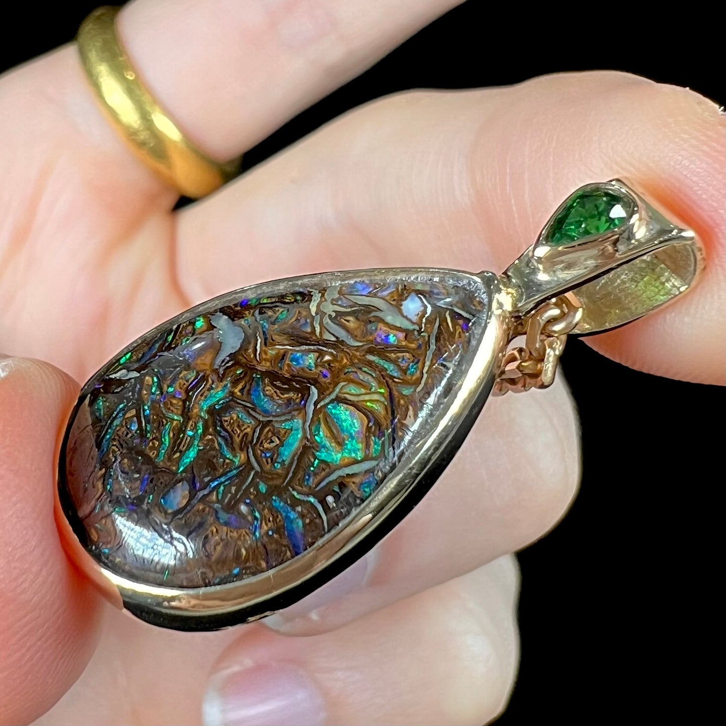 A ladies' yellow gold pendant set with a natural Koroit, Australian boulder opal and a tsavorite garnet accent stone.