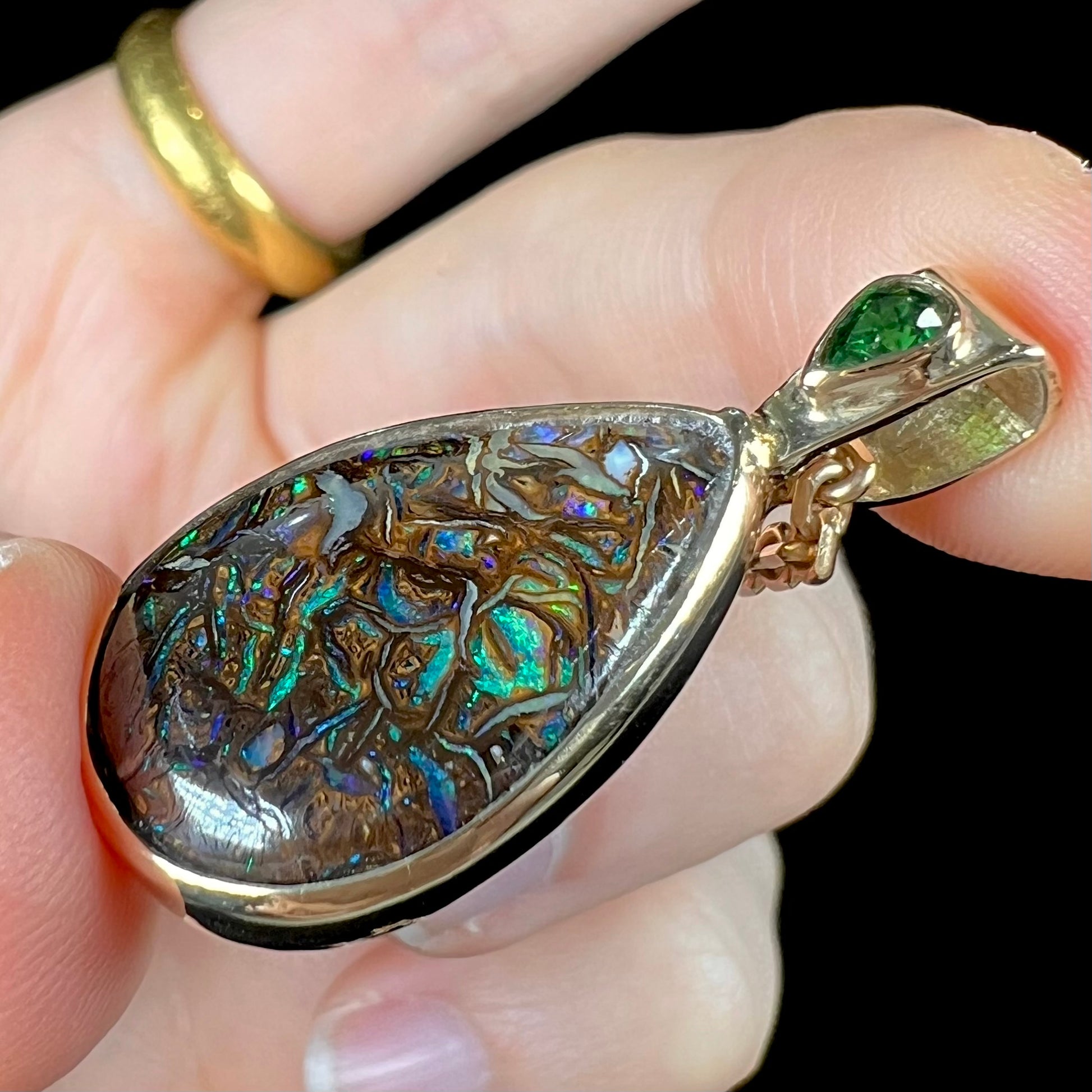 A ladies' yellow gold pendant set with a natural Koroit, Australian boulder opal and a tsavorite garnet accent stone.