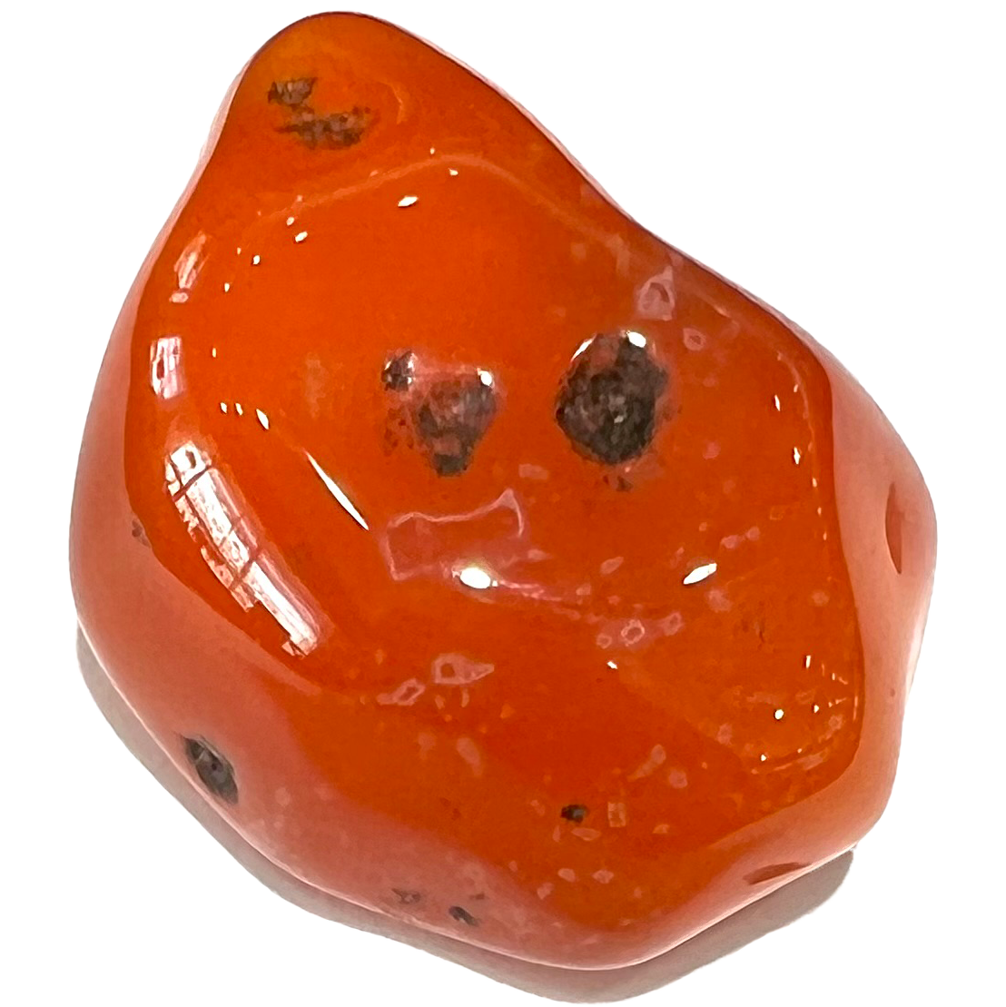 A tumbled carnelian stone.  The stone is bright orange with black pitting.