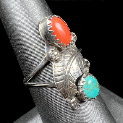 A vintage sterling silver Navajo style ring set with turquoise and coral stones and a feather design.