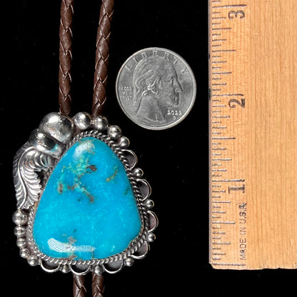 A men's sterling silver, Navajo style bolo tie set with a Pilot Mountain turquoise stone.  The rope is brown leather.