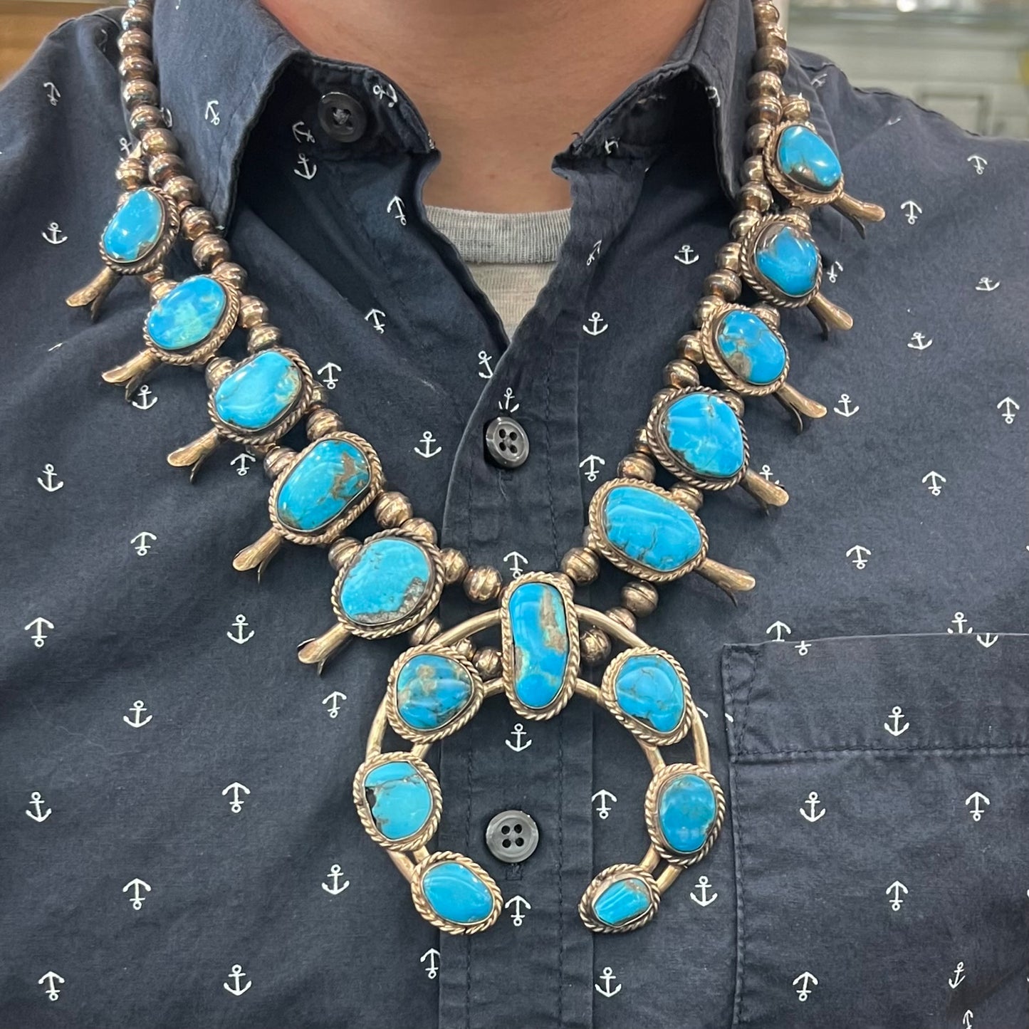 A vintage Navajo squash blossom necklace set with blue Kingman turquoise stones.