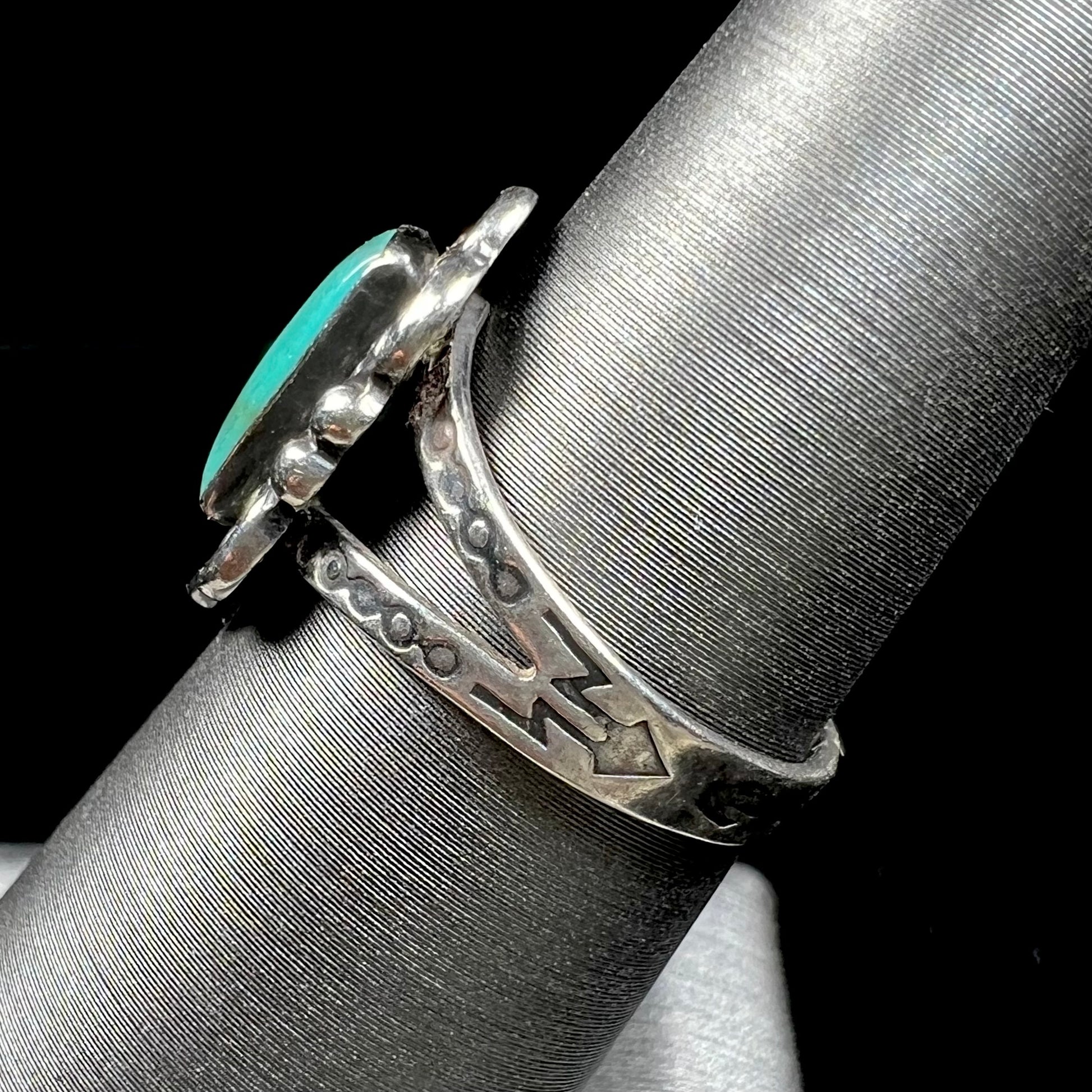 A ladies' silver ring stamped with Southwest style designs and set with a rectangular cabochon cut Royston turquoise stone.