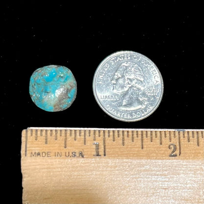 A round cabochon cut Tyrone turquoise stone from New Mexico.  The stone is blue with brown, gray, and black matrix.