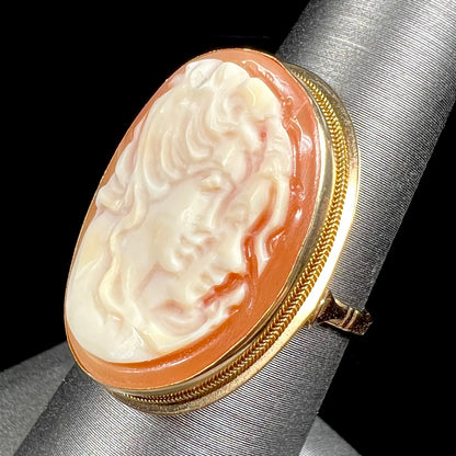 A ladies' vintage cameo solitaire ring in yellow gold.  The cameo is carved from shell and depicts the side profile of two womens' faces.