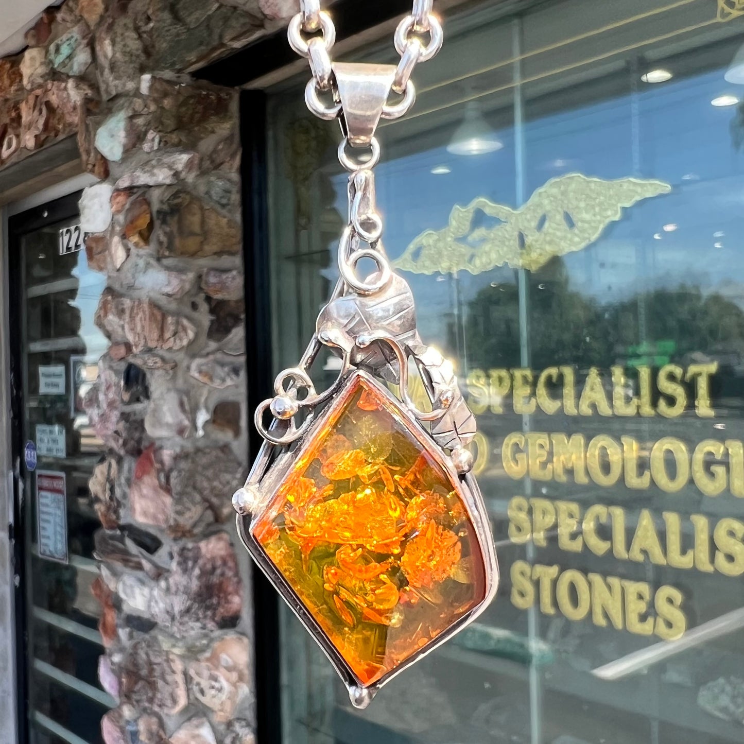 Unisex silver pendant set with a sun-spangled Mexican amber stone, featuring silver leaf design accents.